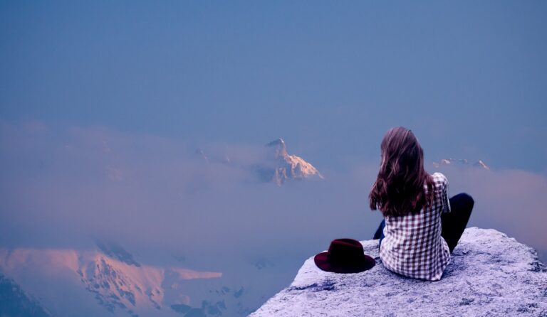 Vrouw zit rustig op een rots boven de wolken en neemt de tijd voor herstel